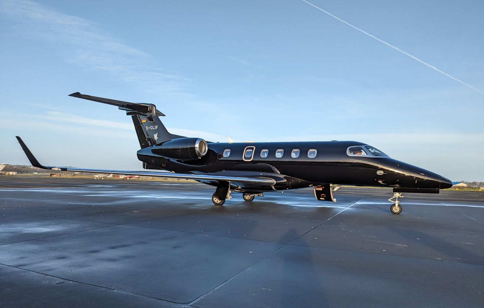 Dark-liveried private jet parked at an airport gate