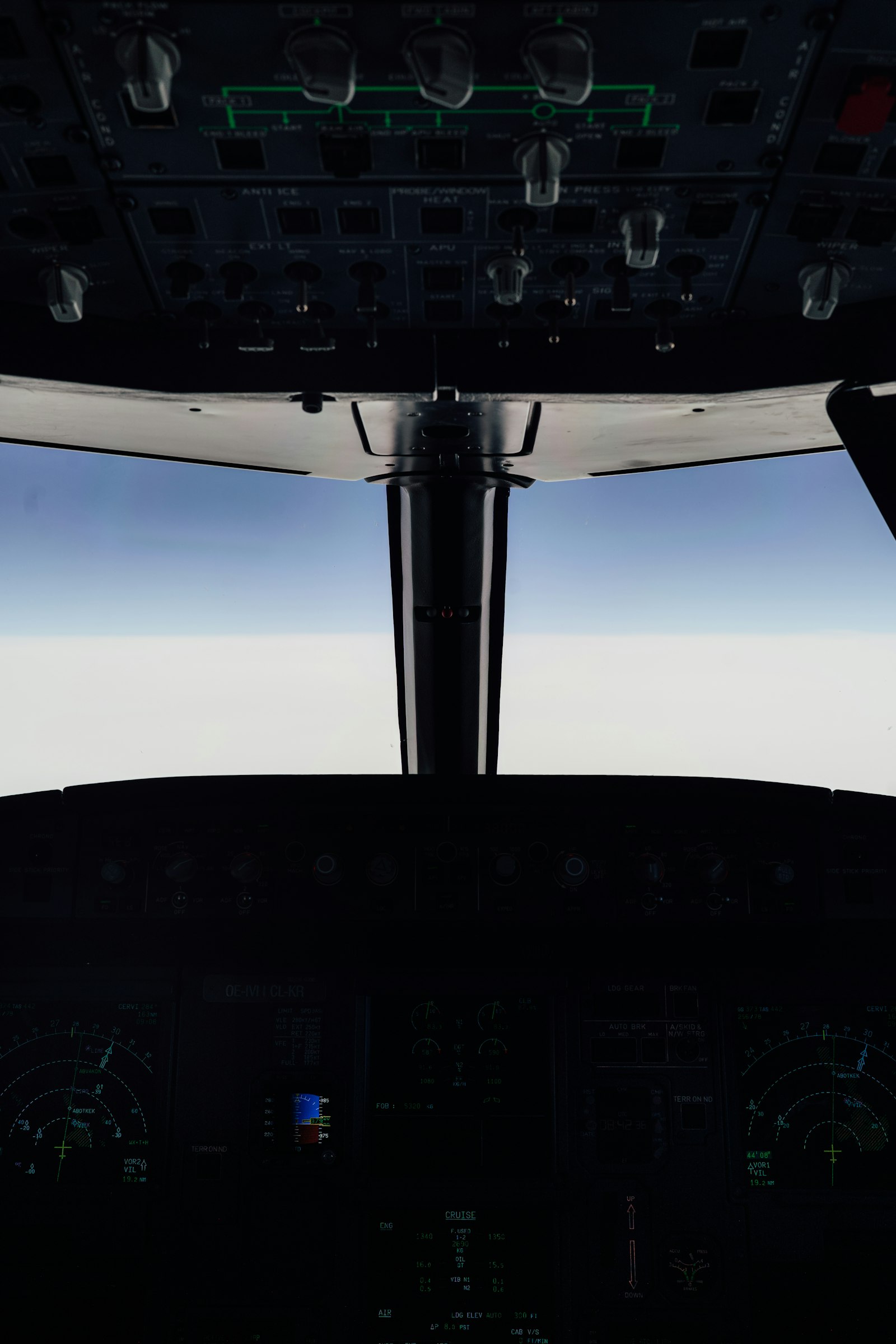 View from an aircraft cockpit above clouds near mountains