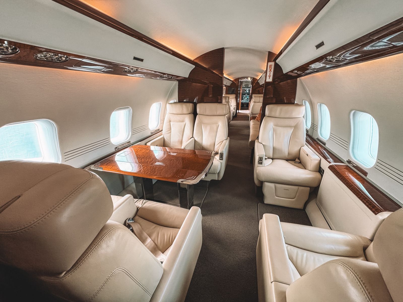 Private jet cabin interior with cream leather seats and wood trim