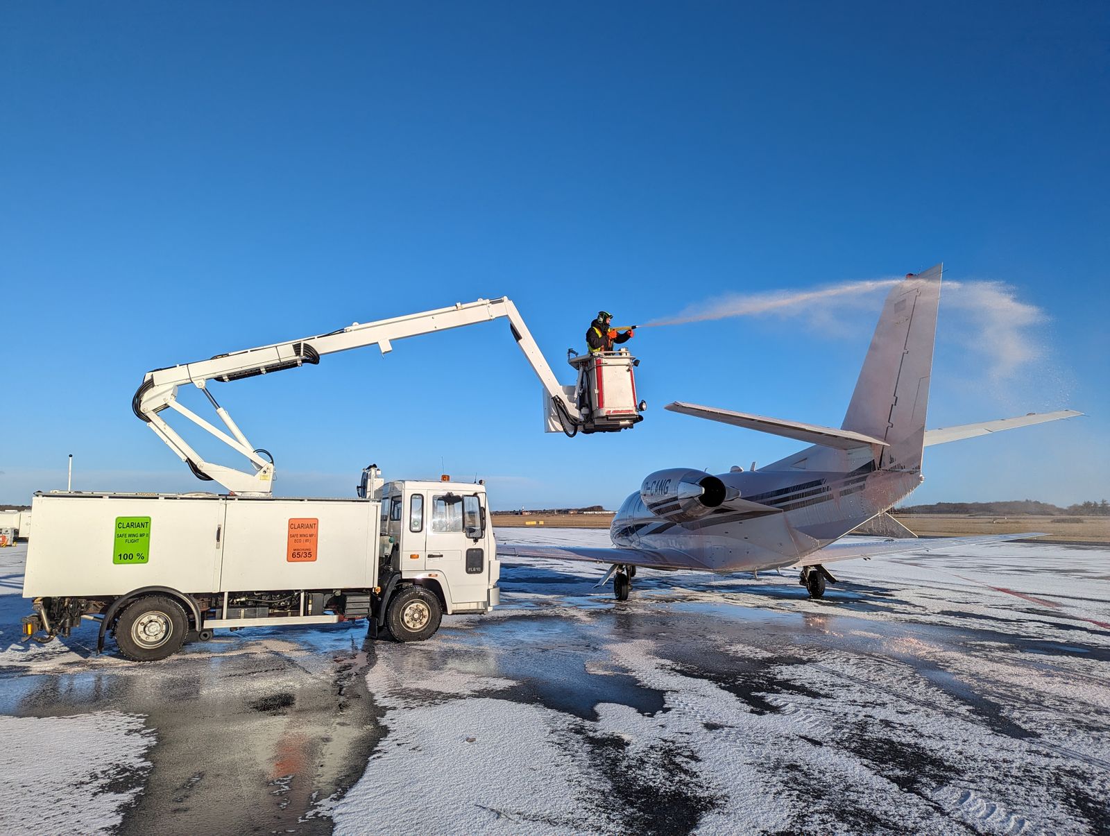 Private jet being sprayed with deicing fluid on a clear winter day
