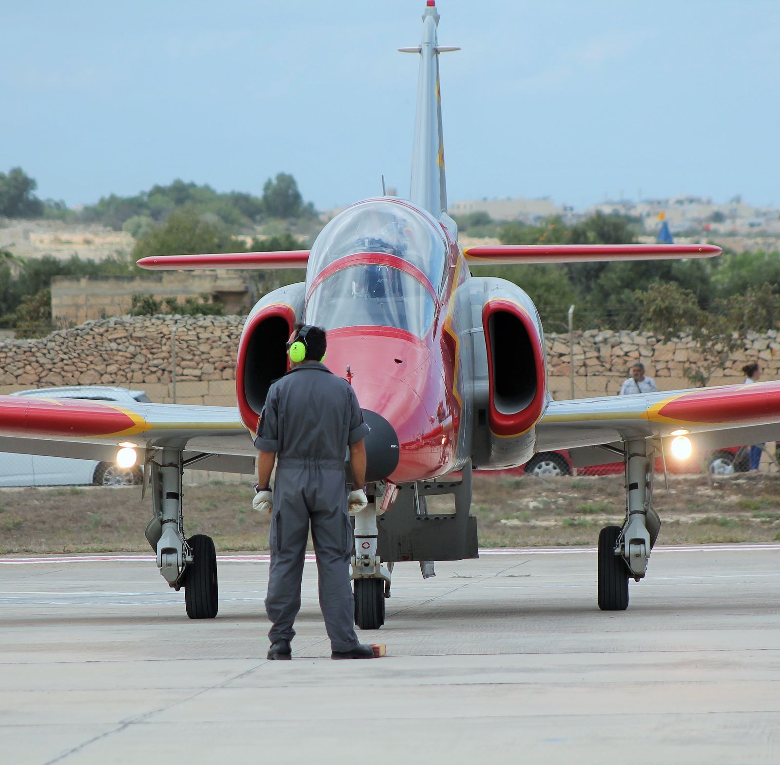 Ground crew marshaller signaling a jet on the tarmac at an airport