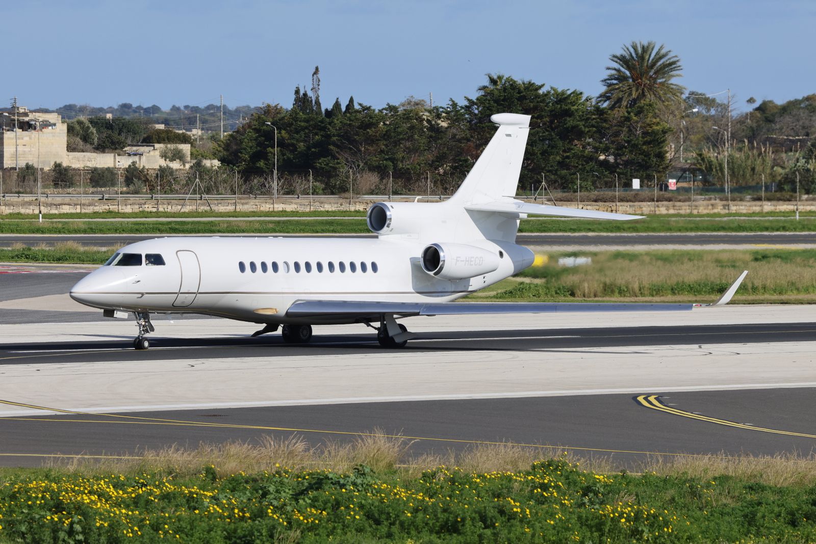 Private jet taxiing on an airport tarmac under a clear blue sky