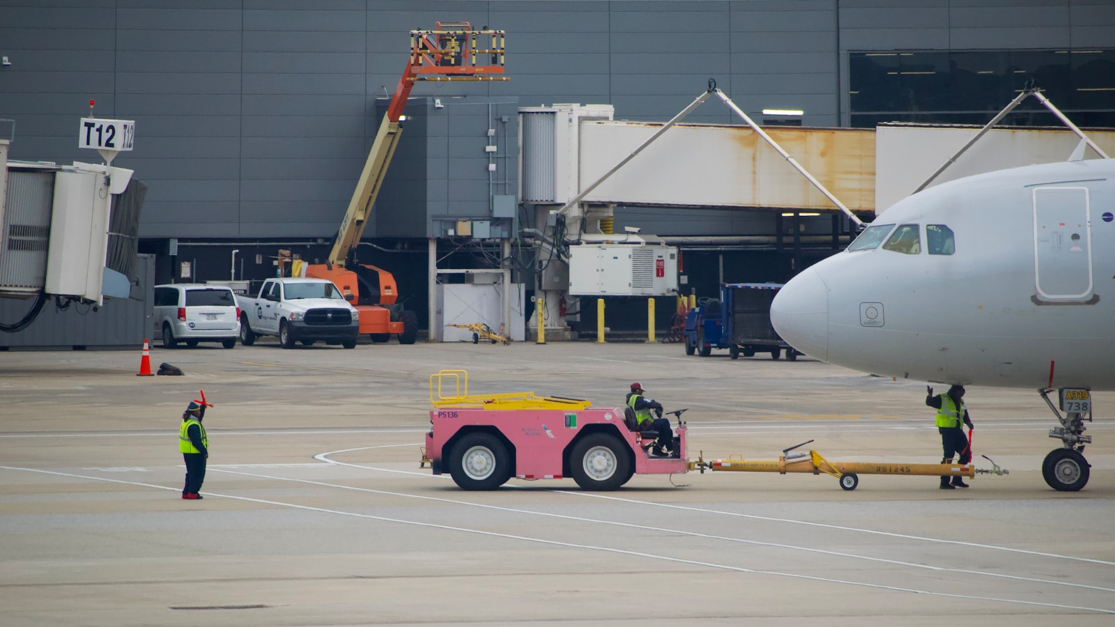 Ground crew detaching a tow tractor from an aircraft on the ramp