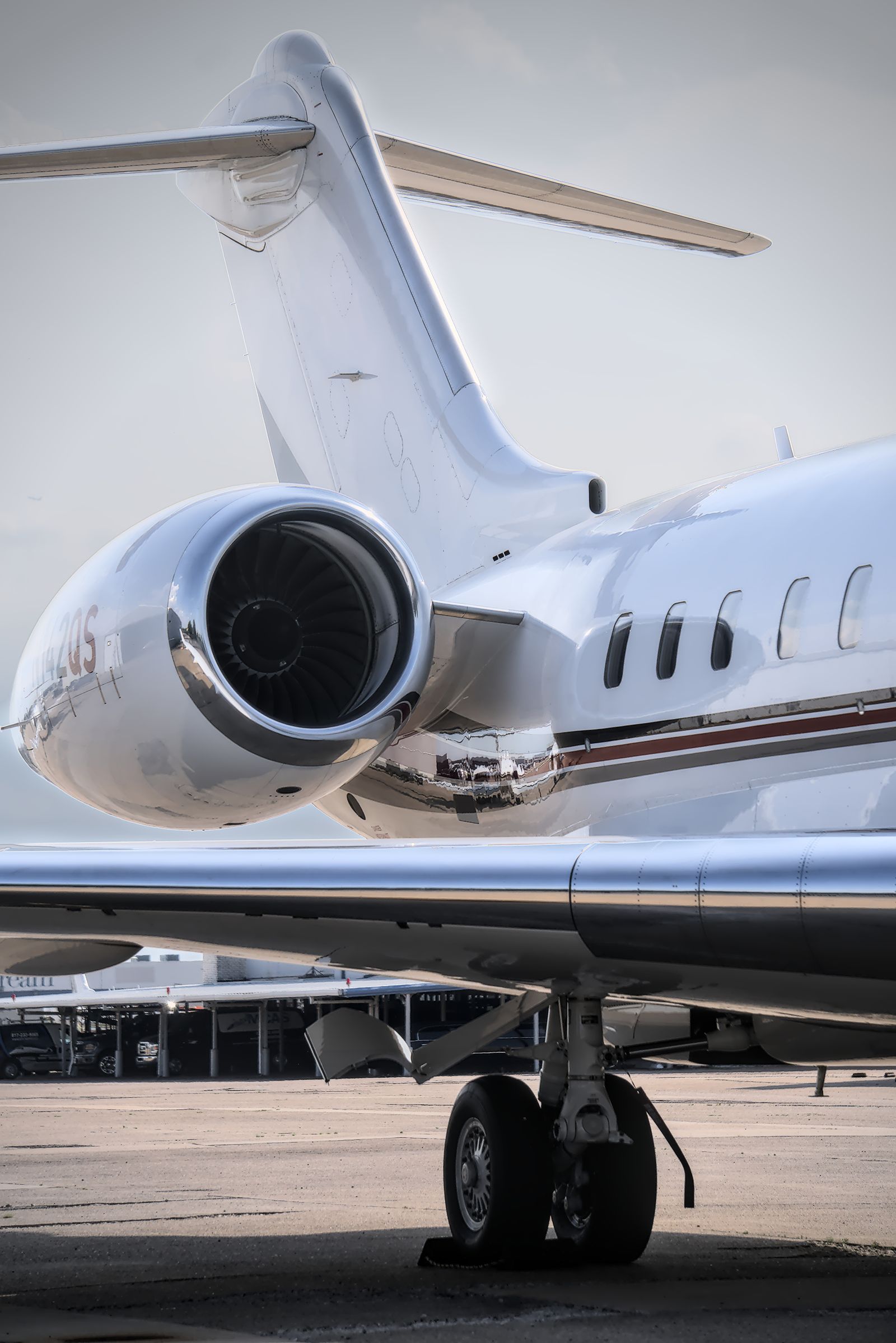 Close-up of a business jet's rear-fuselage engine and a row of oval cabin windows.
